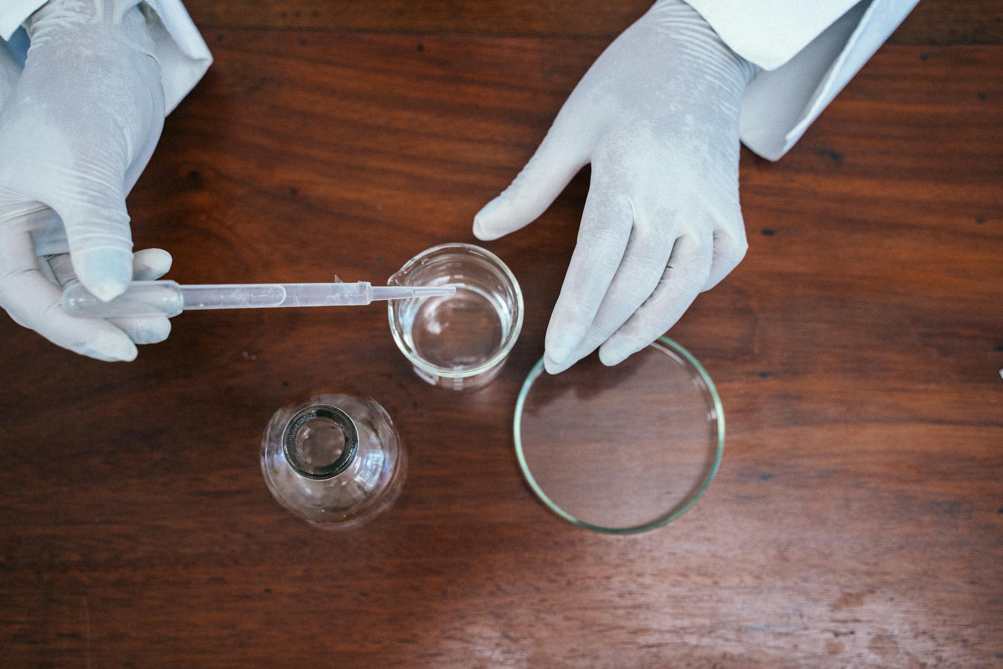 Close-up of a scientist working with lab equipment, wearing gloves, and conducting an experiment.